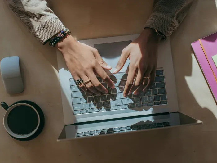 Hands typing on a laptop beside a coffee cup, creating a business listing and managing reviews on Local Biz Map